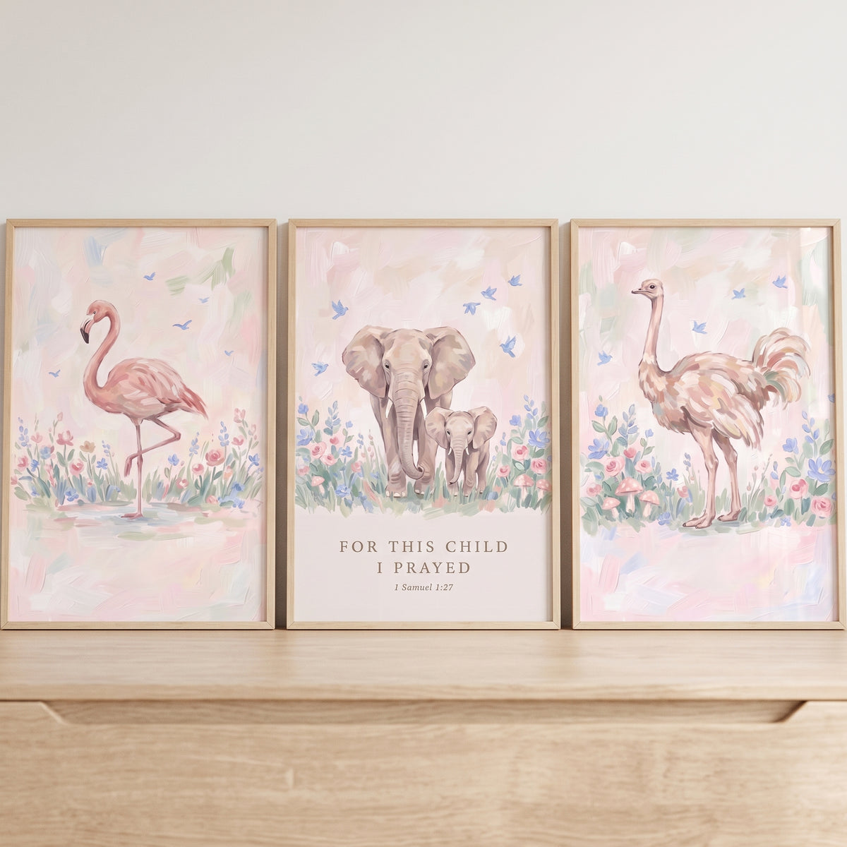 Coastal blush savanna animals wall art set of 3 with a flamingo, elephant pair, and ostrich in soft pastel floral meadows.