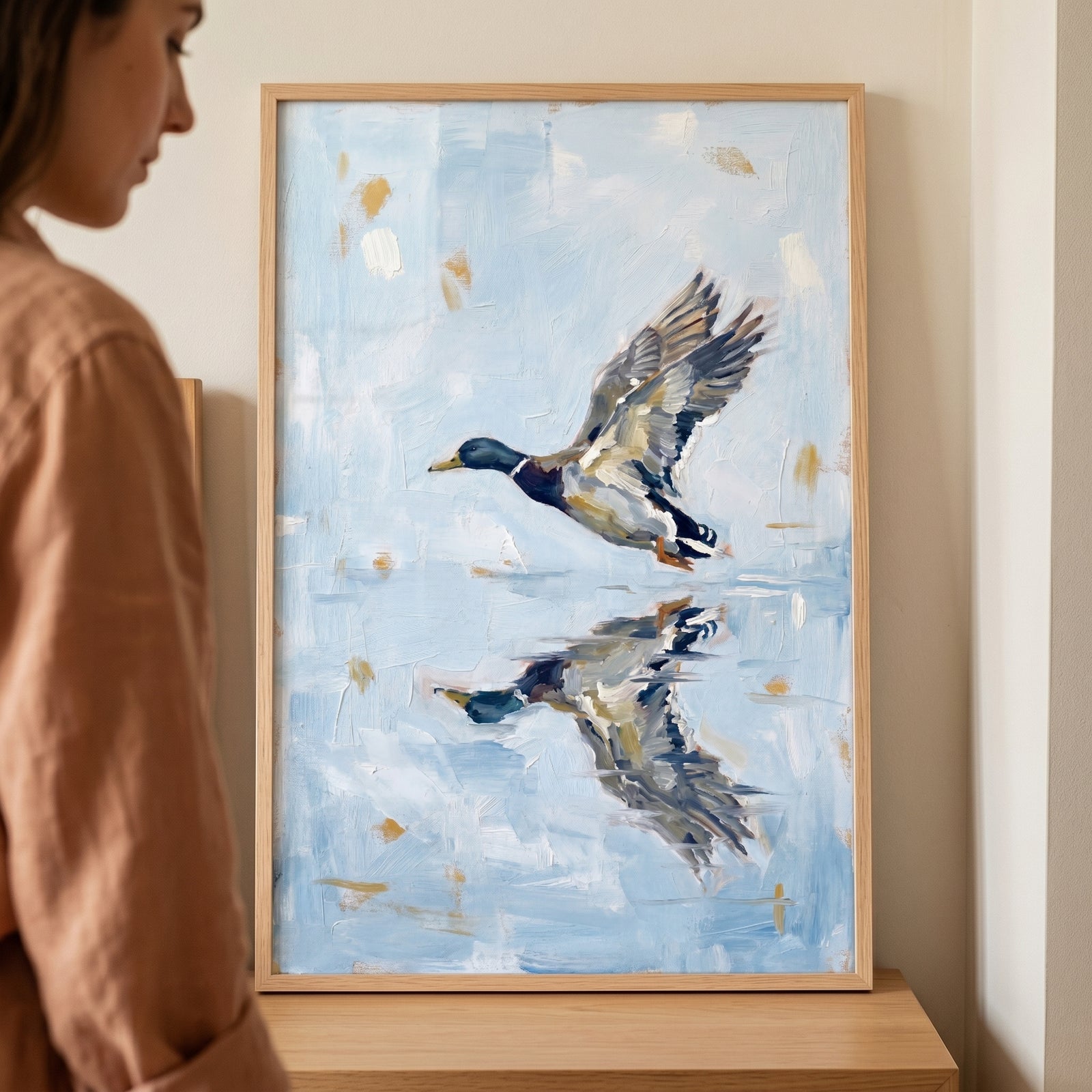 Coastal lakehouse style mallard duck artwork showing a duck in flight and its reflection, set in a light wood frame.
