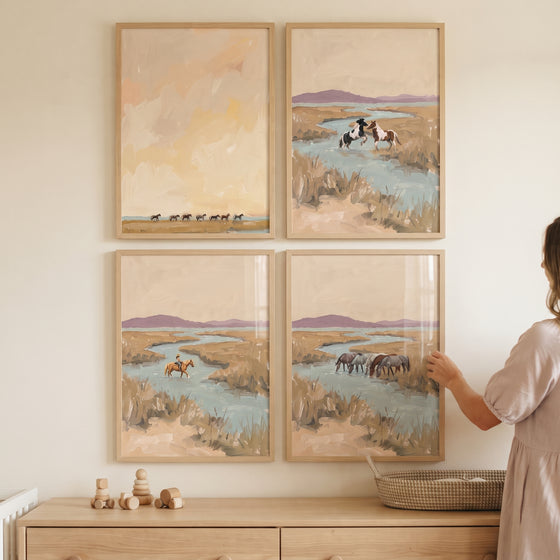 Coastal prairie wild horses wall art set of 4 in wooden frames hangs on a neutral wall above a wooden dresser.