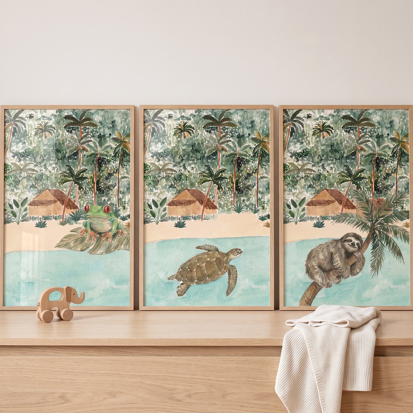 Coastal retreat jungle animals wall art set of 3 features a frog, sea turtle, and sloth in a tropical beach scene.