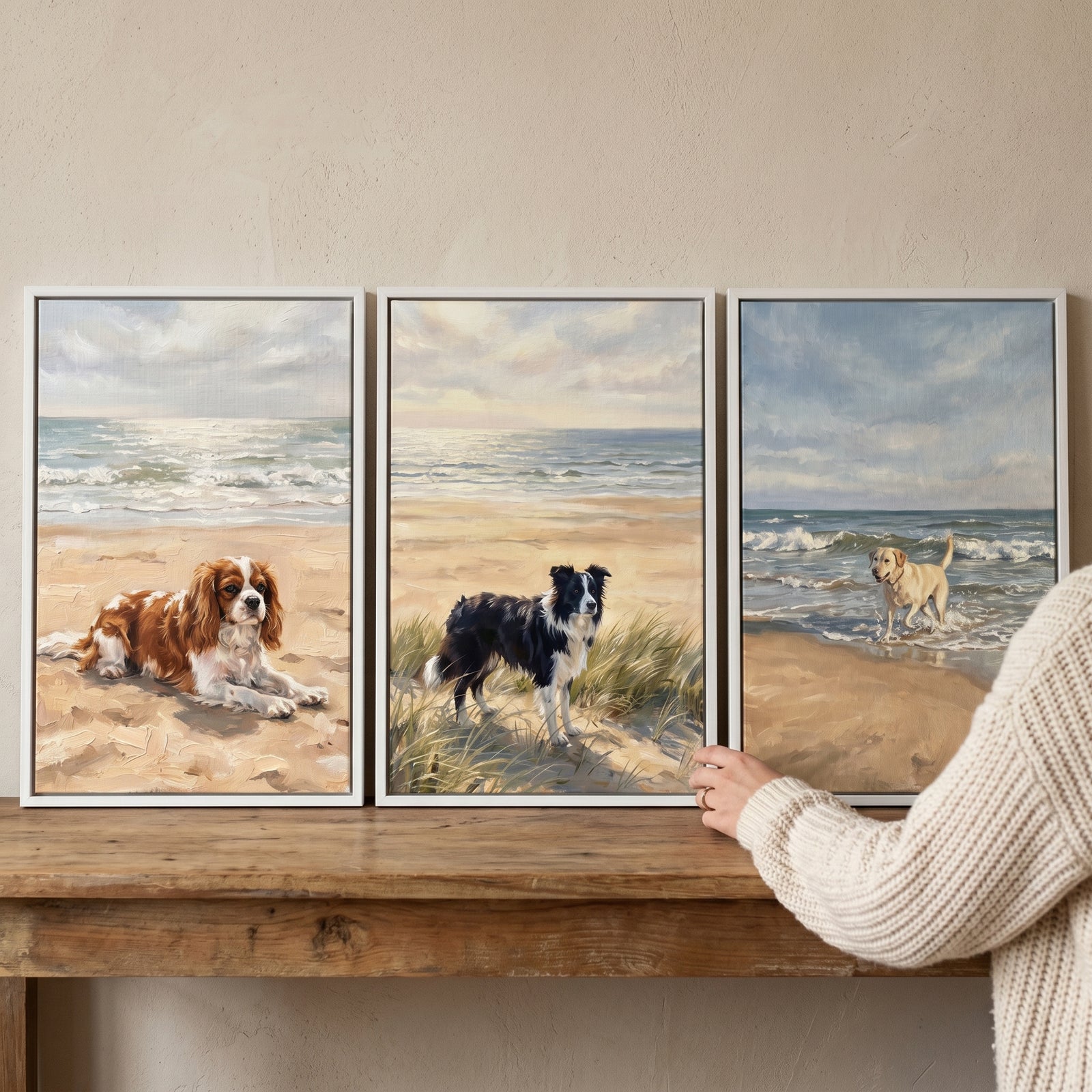 Coastal sandy beach dog wall art set of 3 showing dogs on shores, displayed on a wooden surface with a person's hand.