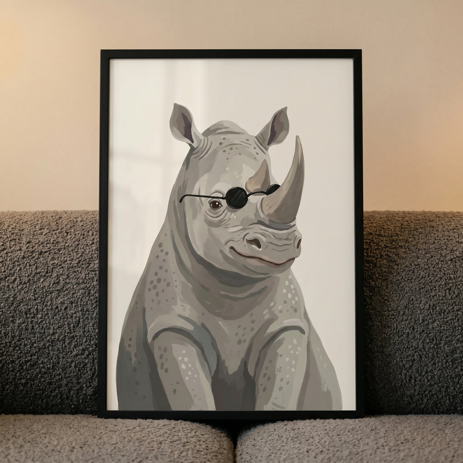 Framed cool black shades rhino artwork of a rhinoceros in round sunglasses, displayed on a gray textured sofa.