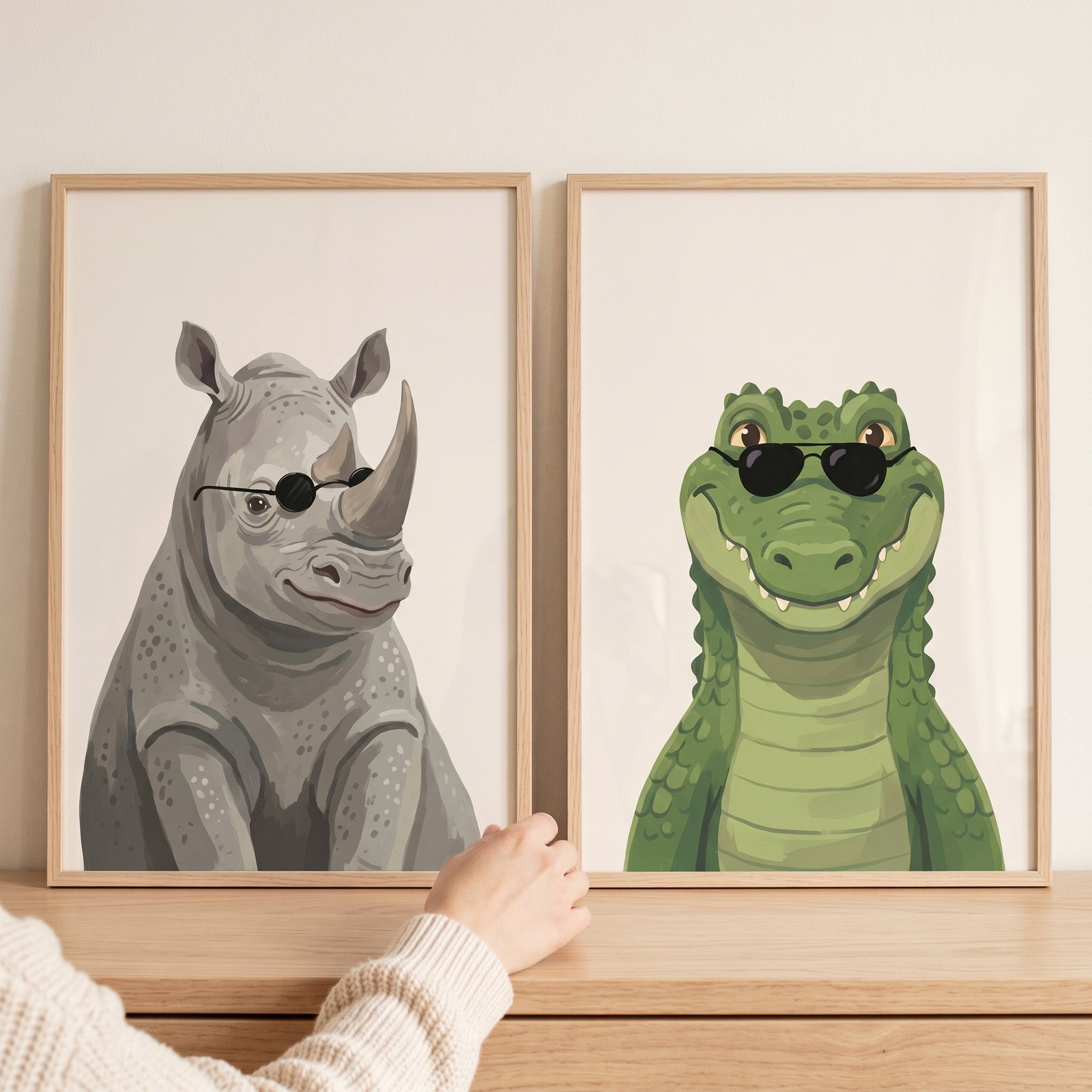 Hand touching cool sunglasses safari animals wall art set of 2 with a rhino and crocodile in light wood frames.