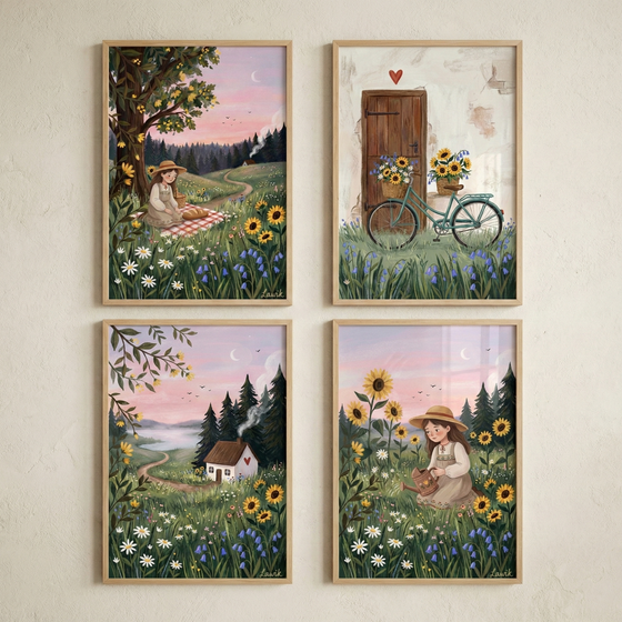 Four framed whimsical illustrations are arranged in a grid on a light-colored wall, depicting peaceful country scenes. One shows a girl on a picnic blanket under a large tree. Another features a teal bicycle with flower-filled baskets by a wooden door. A third depicts a small white cottage with a red heart in a flowery meadow. The final one shows a girl watering sunflowers in a blooming field. Each scene includes soft pink sunset skies, evergreen trees, and various wildflowers.