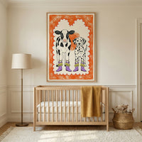Framed whimsical animal art featuring a cow and a dog in boots, hanging above a wooden crib in a warm, cozy nursery decorated in neutral tones with soft textures.