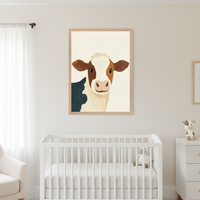 Modern nursery with a white crib. Above it hangs a light wood framed illustration of a brown and white calf. A white dresser with a cow plush and a white armchair are also visible.