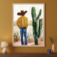 Modern room with a mustard wall and a dark wood console table. A large framed painting hangs centered above the table, depicting a man in a cowboy hat and yellow shirt standing in a desert landscape next to a large cactus, rendered in a brushstroke style.