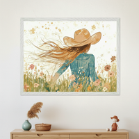 Modern room with a light wood dresser. A white-framed illustration of a woman in a cowboy hat with long, flowing hair in a field of wildflowers hangs centered above the dresser.