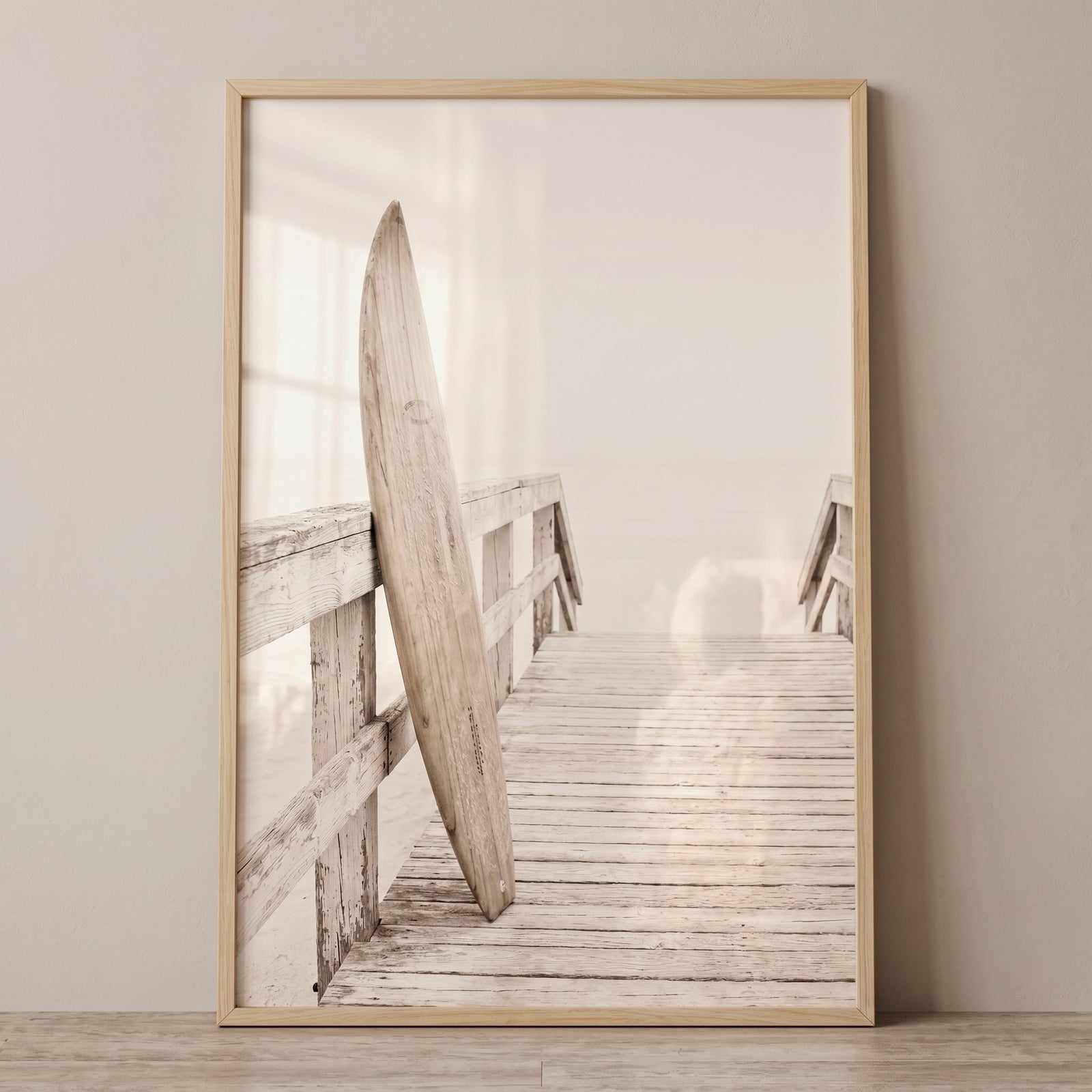 Creamy tones wood surfboard wall art featuring a wooden board leaning on a weathered boardwalk against a soft white sky.