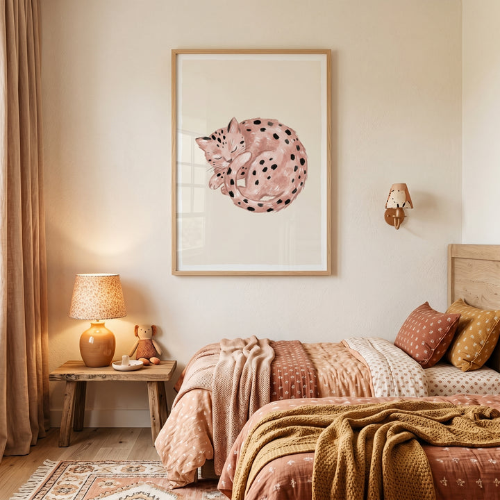 Framed curled up spotted cat wall art hangs above twin beds with warm patterned bedding in a cozy, neutral bedroom.