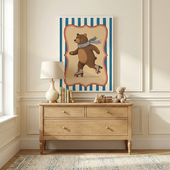 A bright and airy room features a light-colored wooden dresser with three drawers. Atop the dresser sits a lamp with a cream-colored base and white shade, a few small books, a wooden toy train, and a small brown plush bear. Mounted on the wall above the dresser is a framed illustration of a smiling brown bear wearing a patterned scarf and roller skates. The bear is depicted within a decorative red border against a blue and white vertically striped background. 