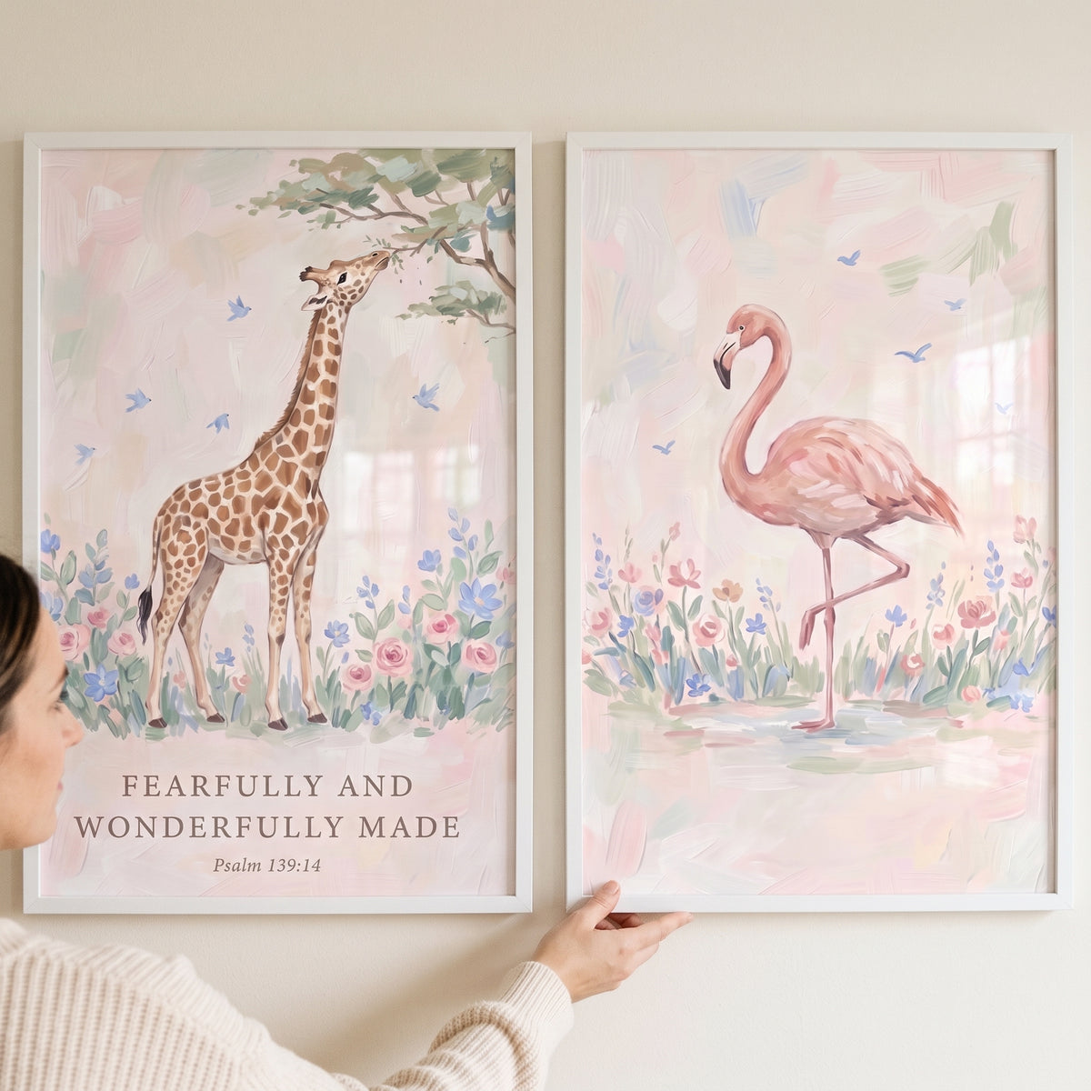 Dainty pink safari animals wall art set of 2 with a watercolor giraffe and flamingo among soft flowers and scripture.