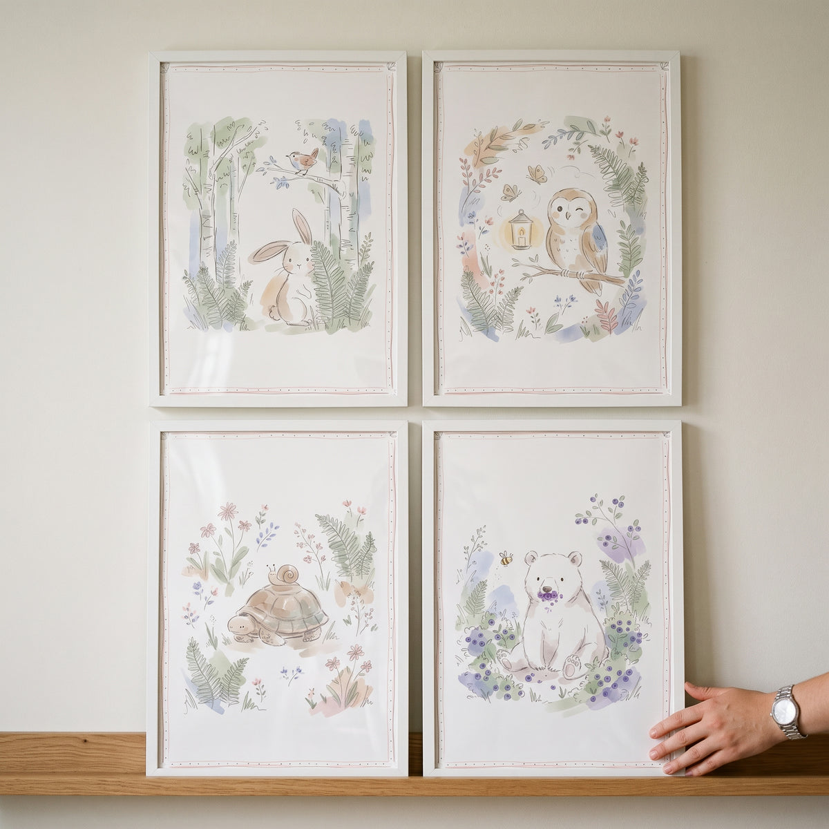 A dainty watercolor woodland animals wall art set of 4 featuring a bunny, owl, turtle, and bear in white frames.