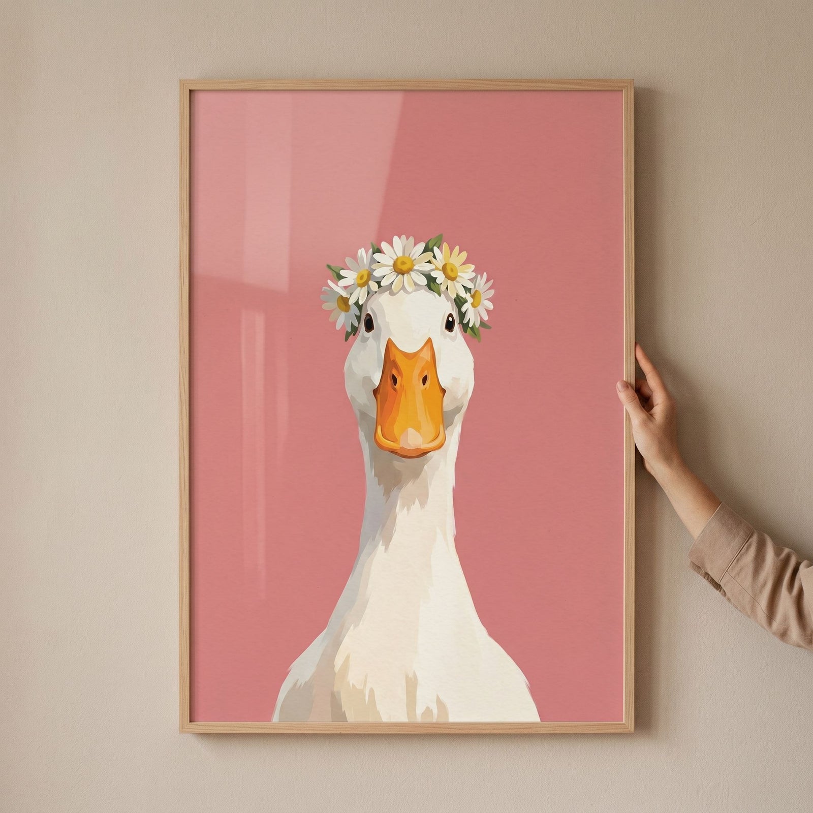 Hand holds daisy crown white goose wall art featuring a white bird with a floral wreath on a solid pink background.