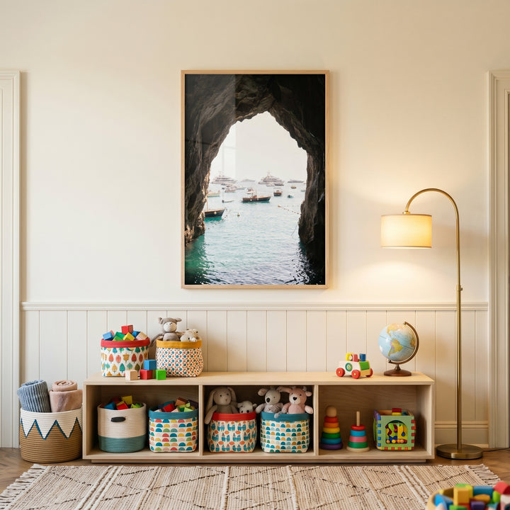 Dark coastal sea cave wall art hangs above a toy storage bench, globe, and floor lamp in a neutral room.