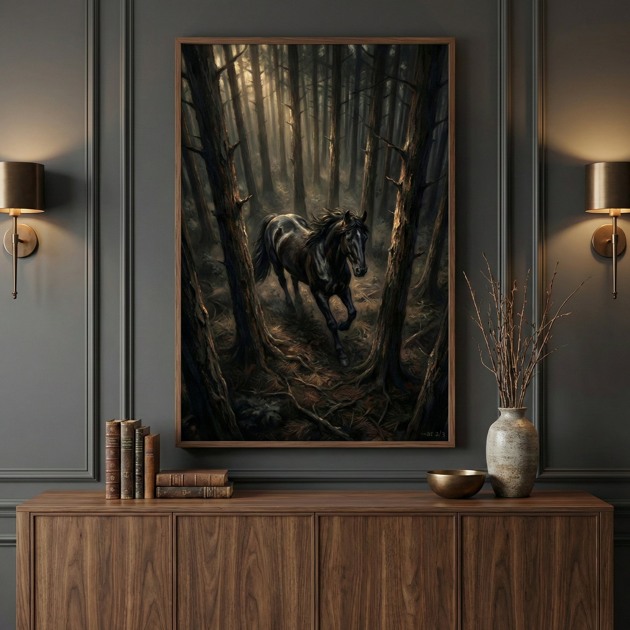 A dark, moody interior features a large, vertically-oriented framed artwork centered on a charcoal gray paneled wall. The artwork depicts a powerful black horse galloping through a dense, shadowy forest with soft light filtering through the trees. Below the frame, a long wooden sideboard holds a stack of vintage books, a small golden bowl, and a tall ceramic vase filled with dried, spindly branches. Two warm-toned wall sconces flank the artwork, casting a soft glow.
