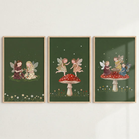 Dark olive forest fairies wall art set of 3 depicts winged figures sitting on grass and atop red spotted mushrooms.