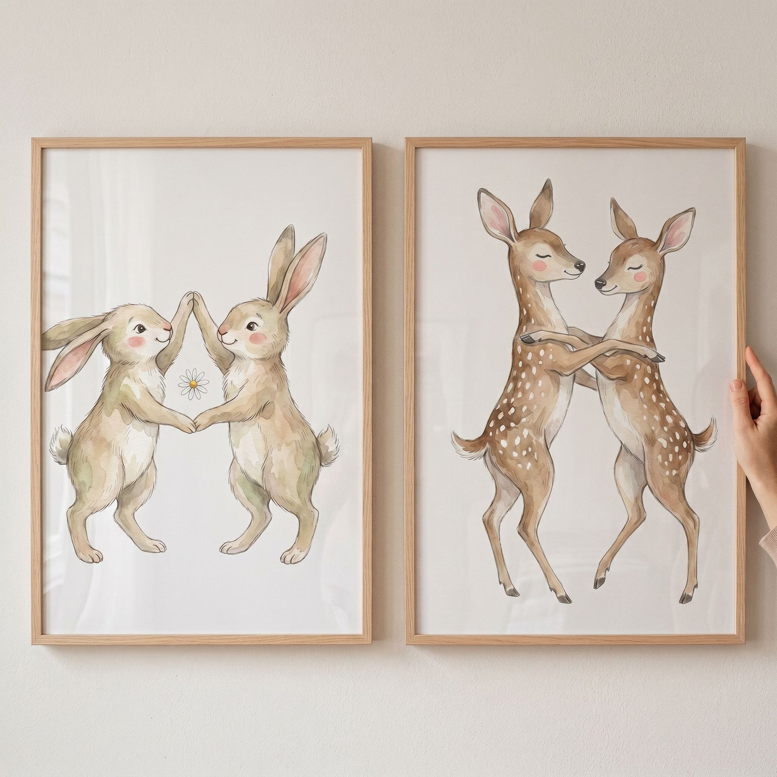 Delicate dancing woodland animal wall art set of 2 with watercolor rabbits and fawns in light wood frames.