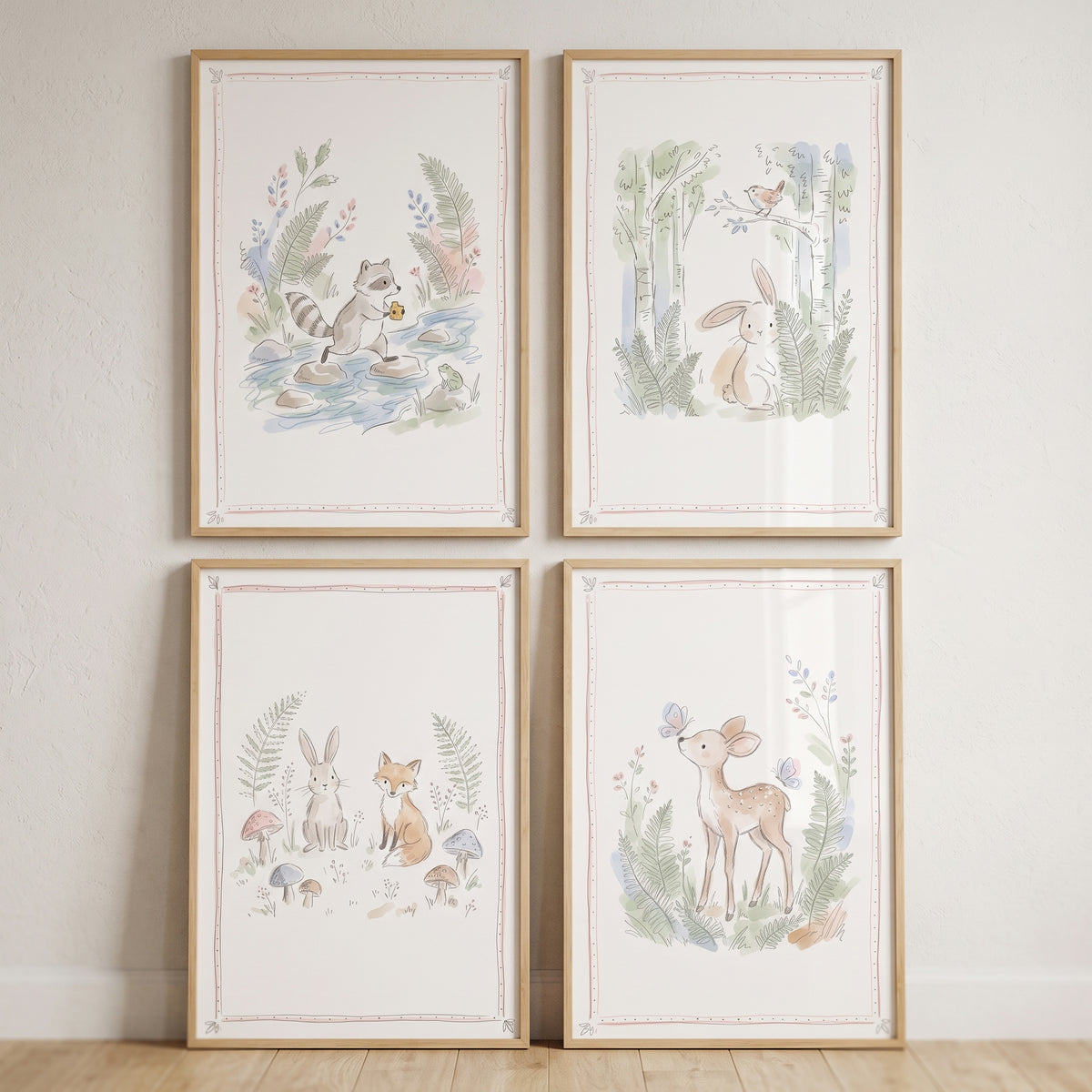 This delicate watercolor forest creatures wall art set of 4 features a raccoon, rabbit, fox, and deer in light wood frames.