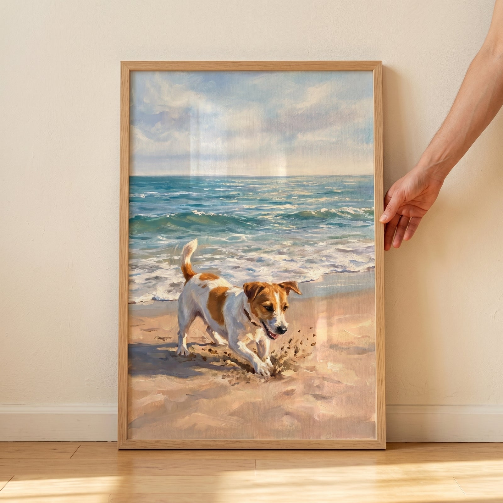 A hand holds a digging sand jack russell dog wall art piece showing a brown and white dog on a beach with ocean waves.