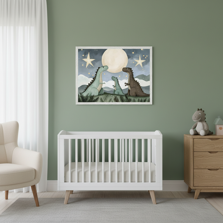 Modern nursery with a white crib, cream armchair, and wooden dresser. A framed print of a dinosaur family, including a baby, under a moon and stars hangs centered above the crib on a green wall.