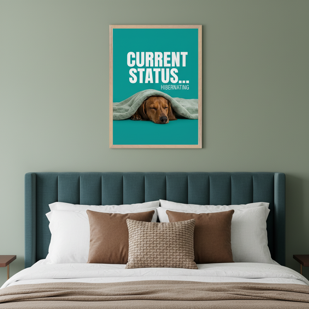 Modern bedroom with a teal upholstered bed. A framed poster hangs above the bed, featuring white text "CURRENT STATUS... HIBERNATING" and a sleeping dachshund dog under a blanket on a teal background.