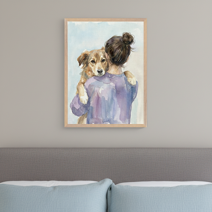 Bedroom with a grey upholstered bed and light blue pillows. A framed watercolor painting of a person hugging a brown dog is centered above the bed.