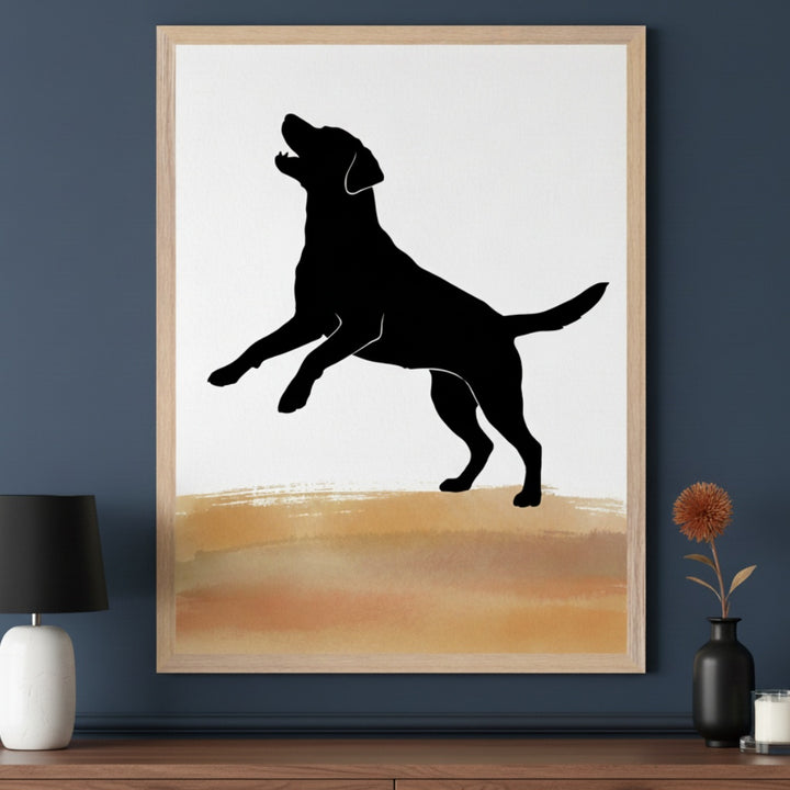 Modern room with a dark blue wall and a wooden dresser. A framed print of a black silhouette of a jumping dog on a white background with a brown and gold watercolor-style band hangs above the dresser. A black lamp and a small vase with a dried flower are on the dresser.