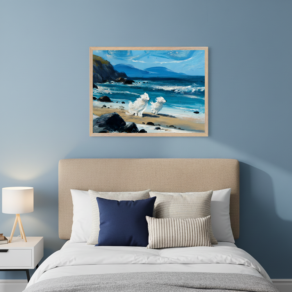 Modern bedroom with a beige upholstered bed and a white nightstand. Above the bed hangs a framed art of two white fluffy dogs playing on a rocky beach with blue ocean waves and distant mountains.
