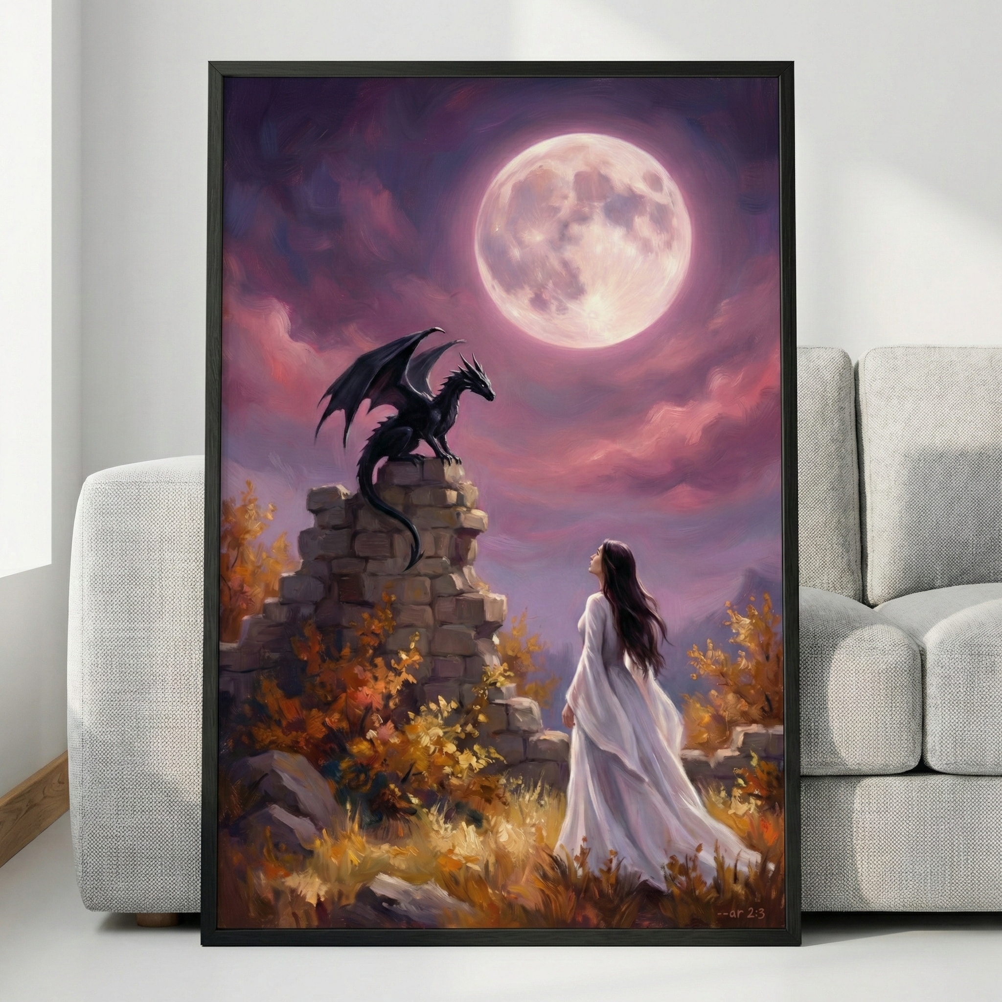 A framed vertical art piece sits against a white wall next to a light gray couch. The illustration depicts an ethereal fantasy scene featuring a woman in a long white dress standing in a golden-brown field. She looks up toward a small black dragon perched on stone ruins. Overhead, a massive, luminous full moon illuminates a sky filled with deep purple and soft pink clouds, creating a mystical and serene atmosphere.