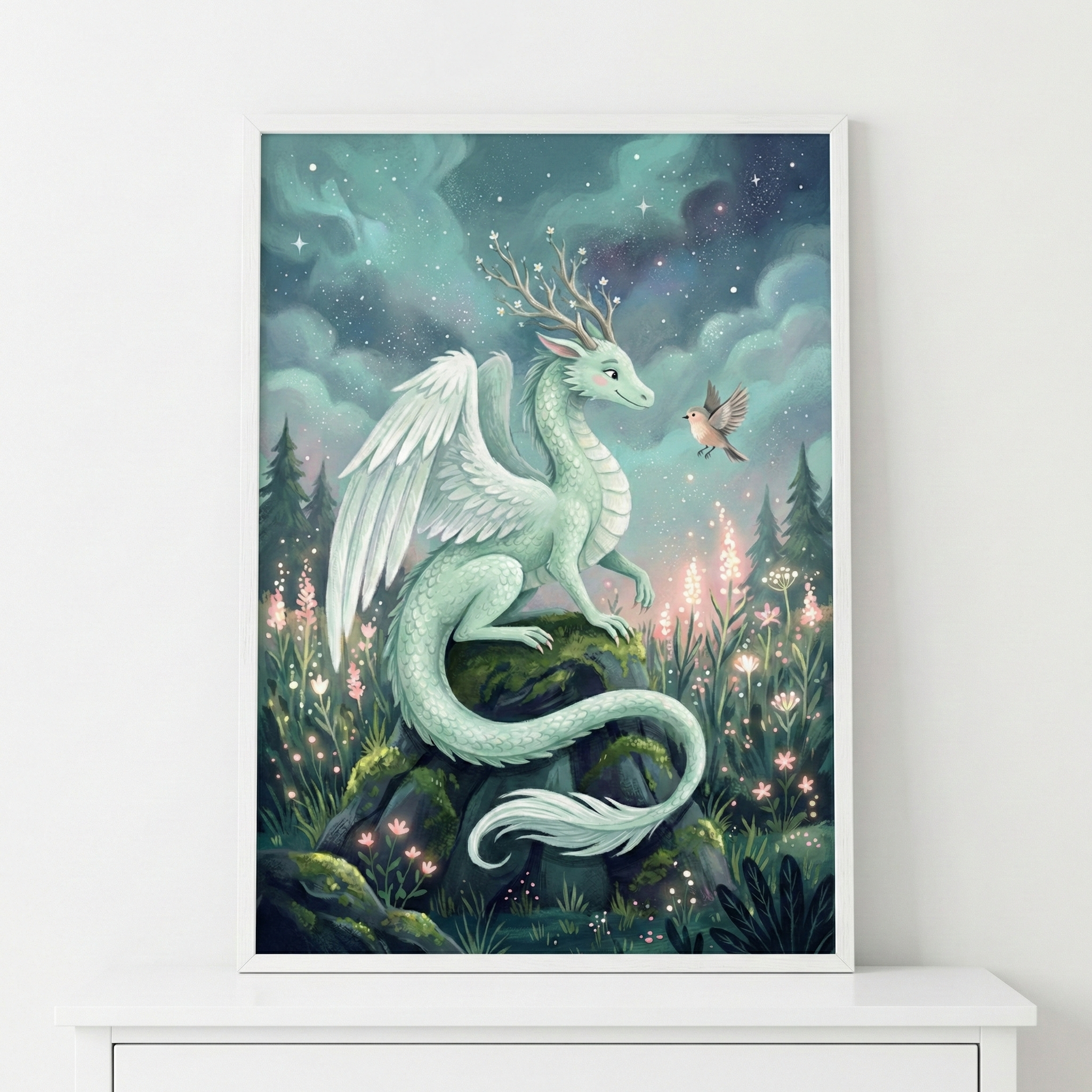 A framed vertical illustration depicts a gentle, mint-green dragon with large white feathered wings resting on a mossy rock. Its head is crowned with wooden antlers sprouting delicate white flowers. The dragon's long tail gracefully curls at the base of the rock. A small bird hovers nearby as if in conversation. They are surrounded by a lush field of glowing pink and white wildflowers against a mystical backdrop of swirling night clouds, shimmering stars, and soft celestial light.