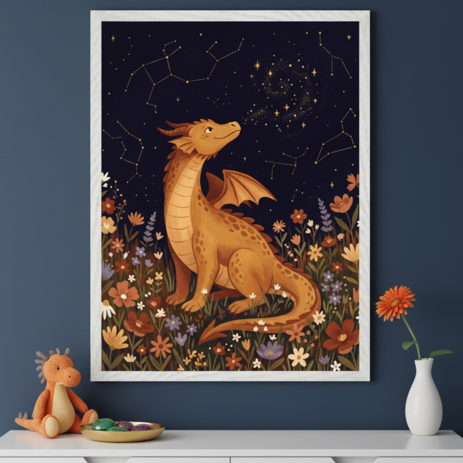Kid's room with a white dresser against a dark blue wall. A large framed illustration of a golden dragon sitting in wildflowers under a starry night sky with constellations hangs centered above the dresser.