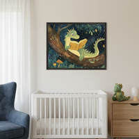 Modern nursery with a white crib, blue armchair, and wooden dresser. A framed print of a green, illustrated dragon reading a book while sitting in a tree hangs centered above the crib and dresser.