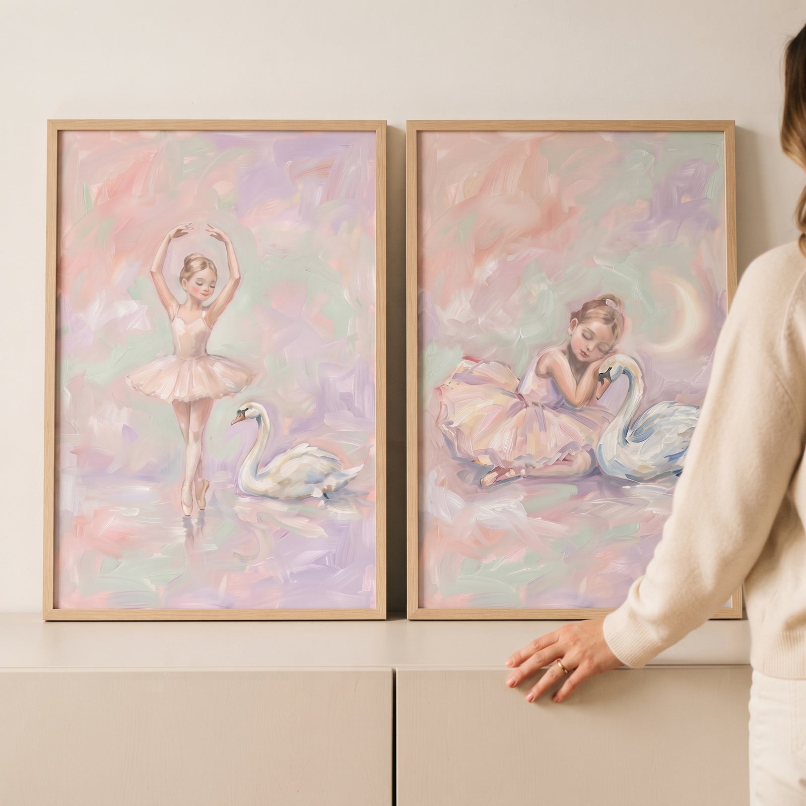 Two pastel frames show ballerinas and swans. This dreamy blush swan ballet wall art set of 2 features soft pink and purple.