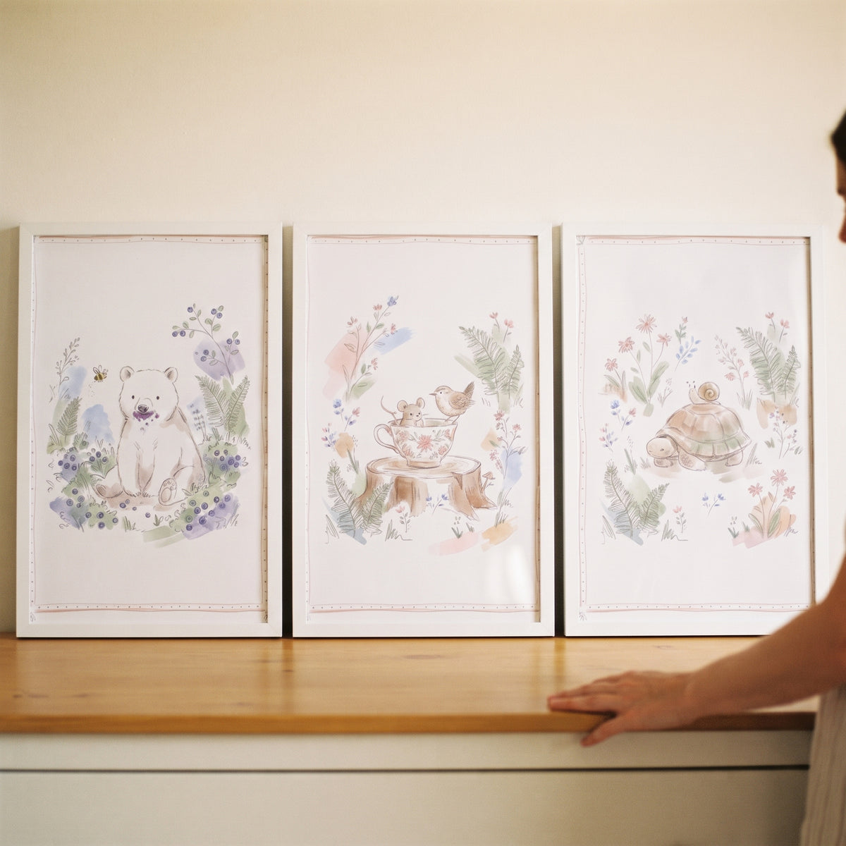 Dreamy botanical woodland animal wall art set of 3 featuring a bear, mouse, and turtle in white frames on a wooden table.