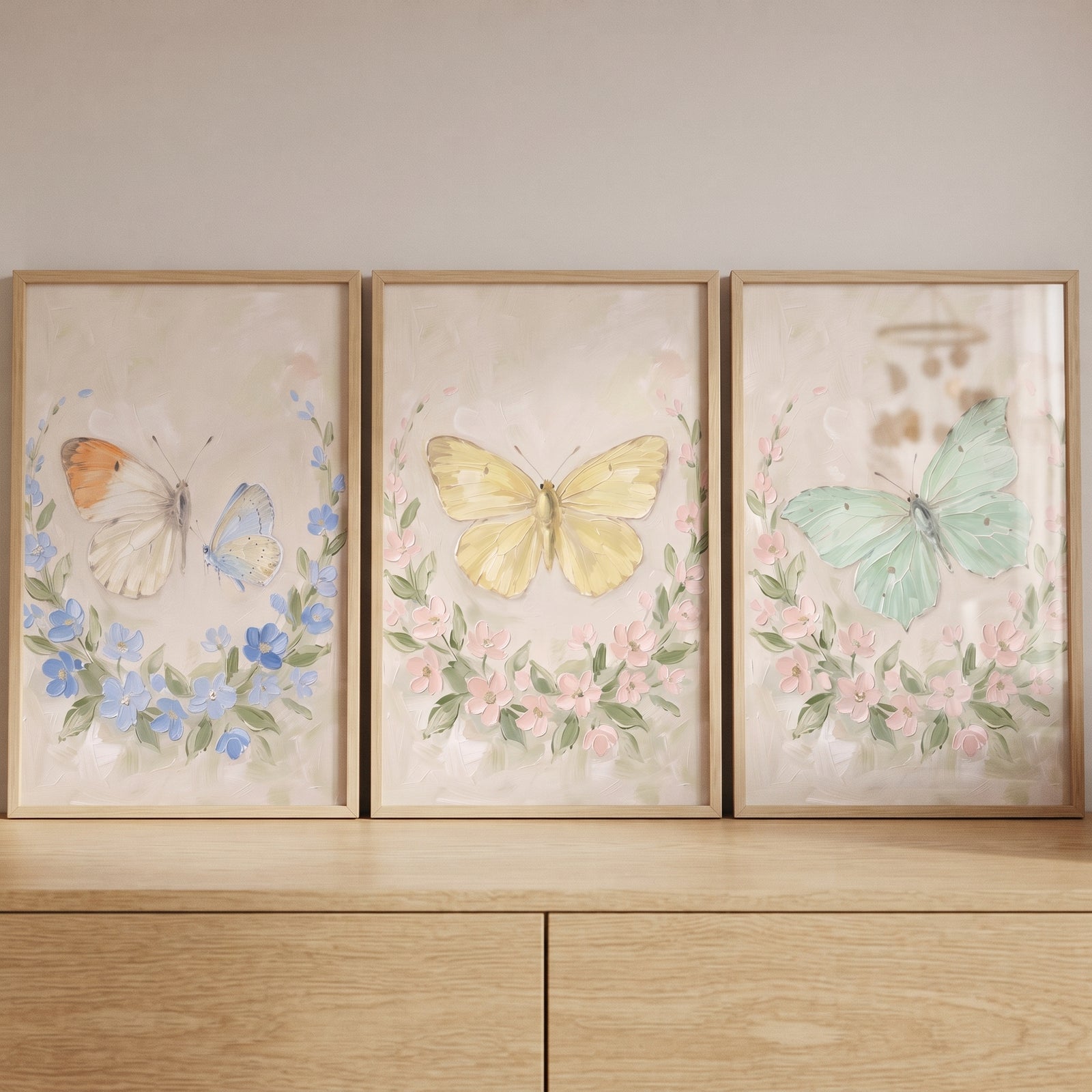 Dreamy garden floral butterfly wall art set of 3. Three framed prints of butterflies and wreaths on a wood dresser.