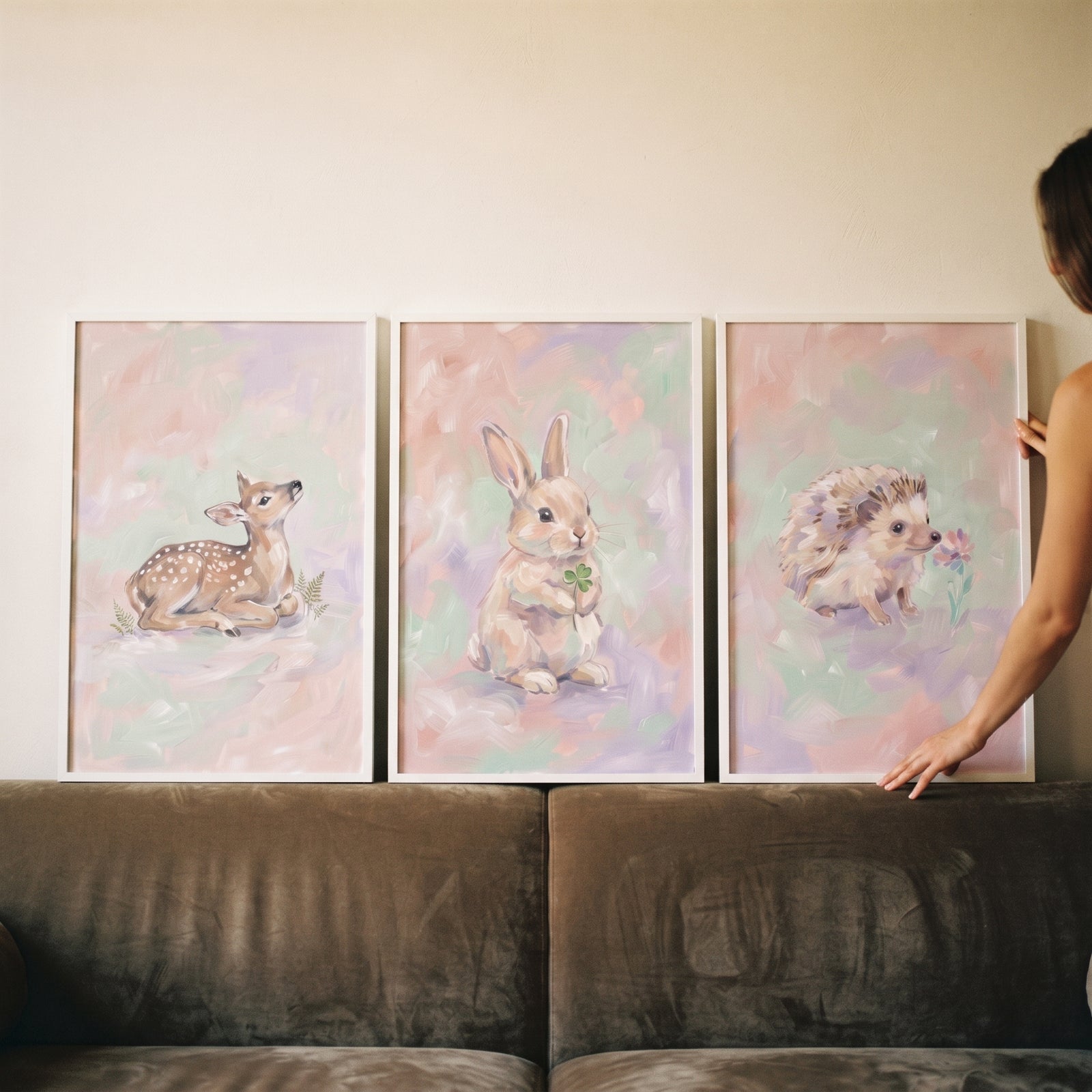Dreamy lavender woodland animal wall art set of 3 featuring a deer, rabbit, and hedgehog displayed on a sofa.