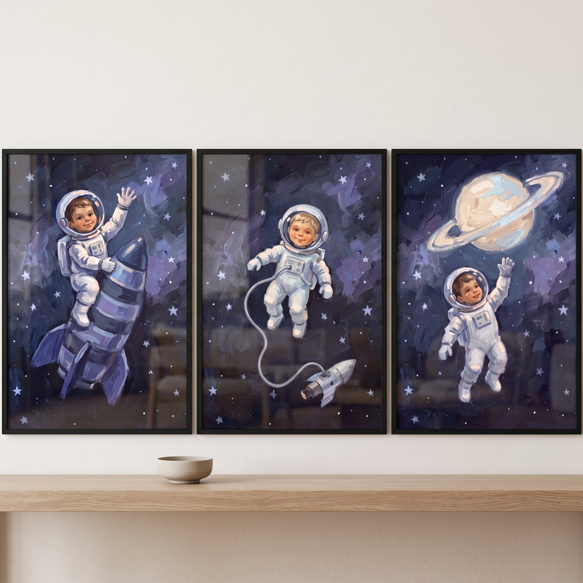 Dreamy starry baby astronaut wall art set of 3 depicts infants in space suits with a rocket, stars, and a ringed planet.