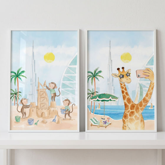Watercolor dubai beach safari animal wall art set of 2 with monkeys building a sandcastle and a giraffe taking a selfie.