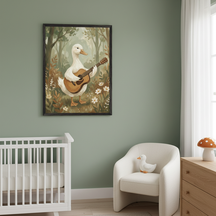 Modern nursery with sage green walls. A framed painting of a white duck playing an acoustic guitar in a forest hangs above a white crib. A cream armchair and wooden dresser are to the right.