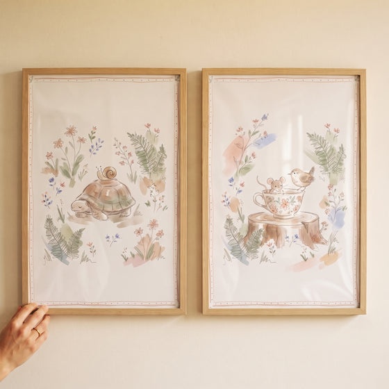 Watercolor turtle, snail, bird, and mouse in a dusty floral woodland animal wall art set of 2 within light wood frames.