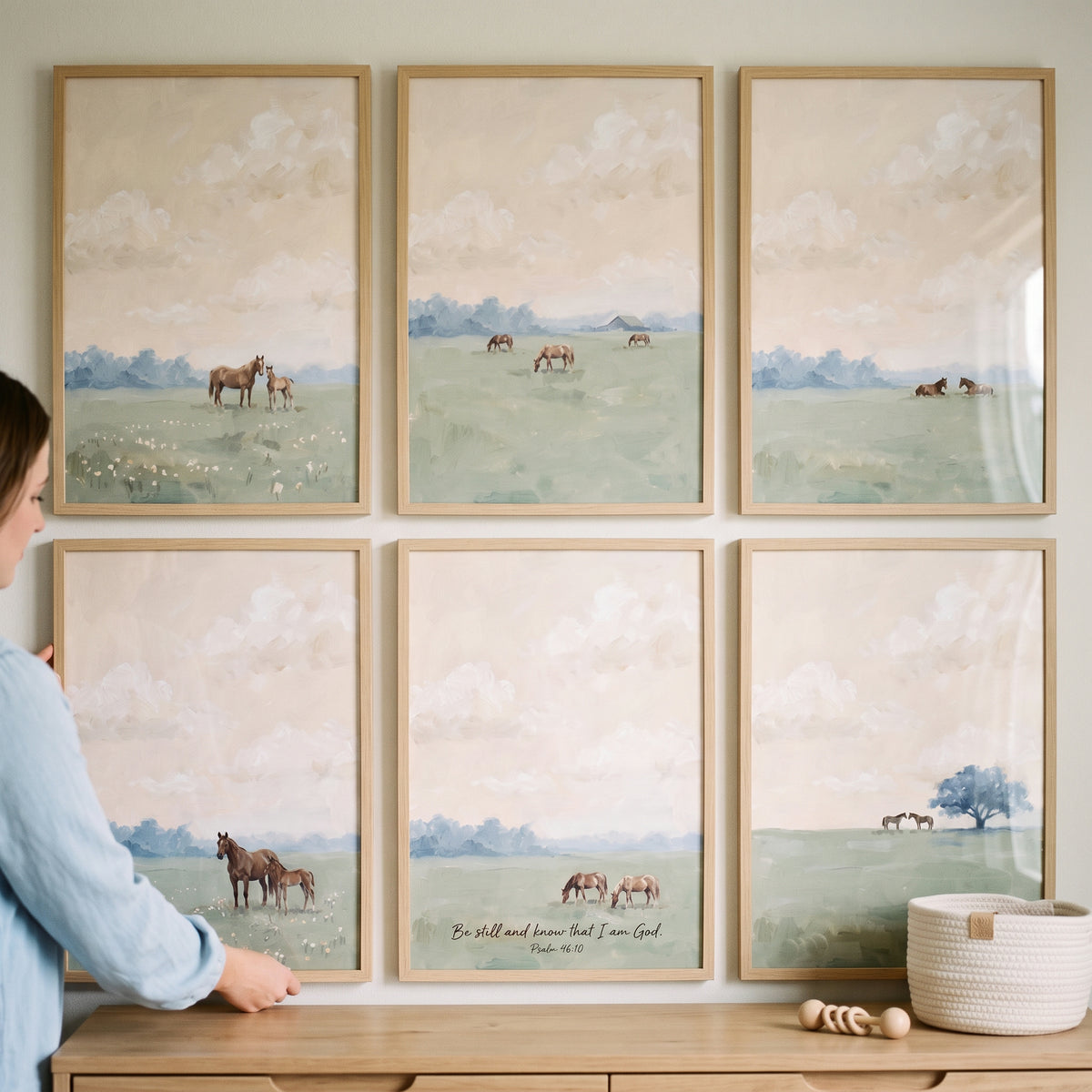 Dusty olive meadow horses wall art set of 6 in wooden frames. A person adjusts one frame above a console table.
