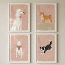 Four framed illustrations of dogs are displayed in a two-by-two grid on a wall. Each image features a different breed against a soft pink background with tiny stars. Top left: a white poodle with a red bow looking at a flower. Top right: a tan and white dog standing on a small hill.