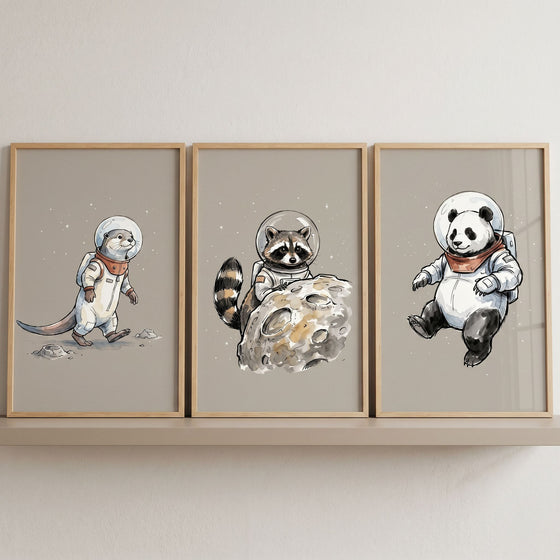 Earthen tone astronaut animal wall art set of 3 featuring an otter, raccoon, and panda in spacesuits on neutral backgrounds.
