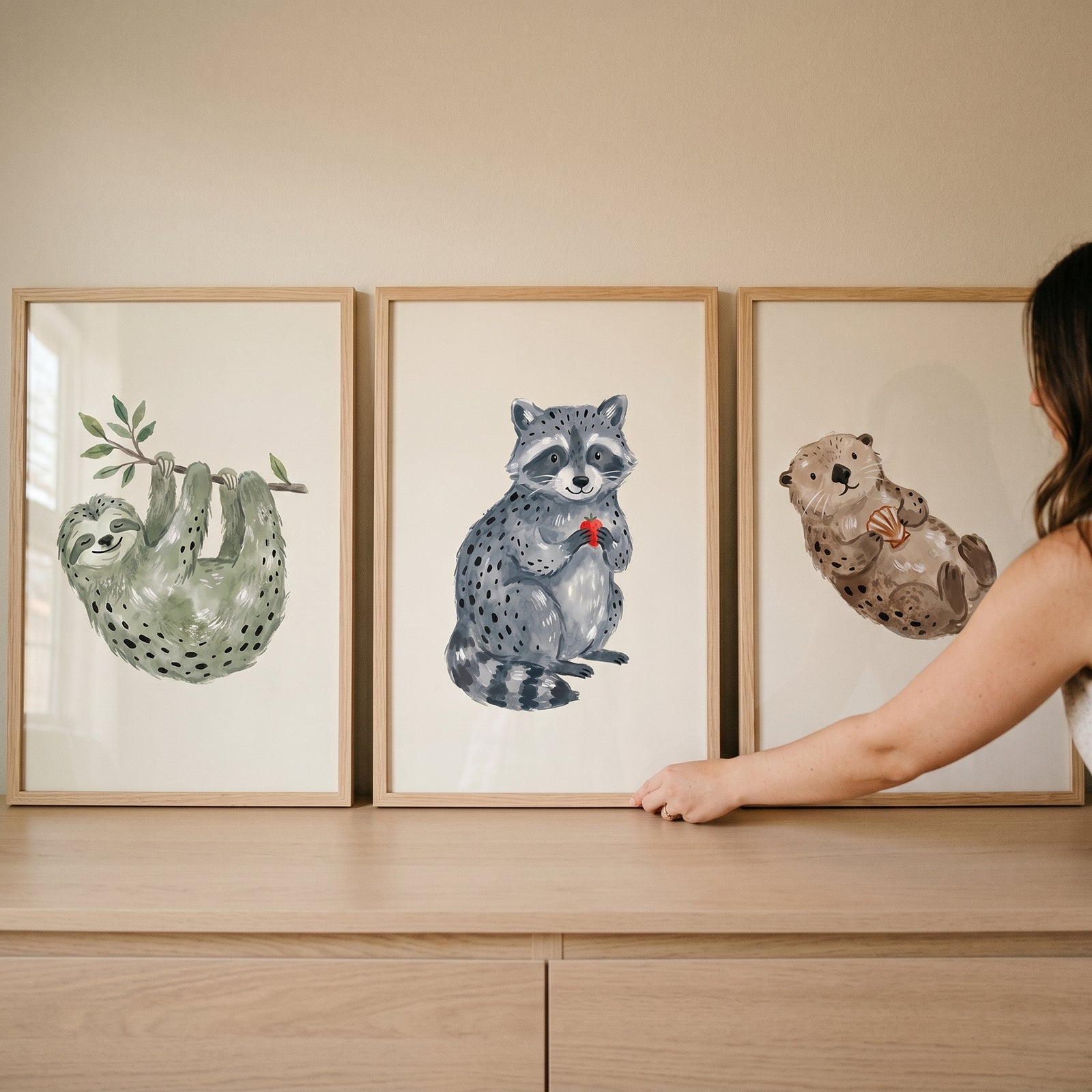 Earthy minimalist watercolor animals artwork set of 3 featuring a sloth, raccoon, and otter in light wooden frames.