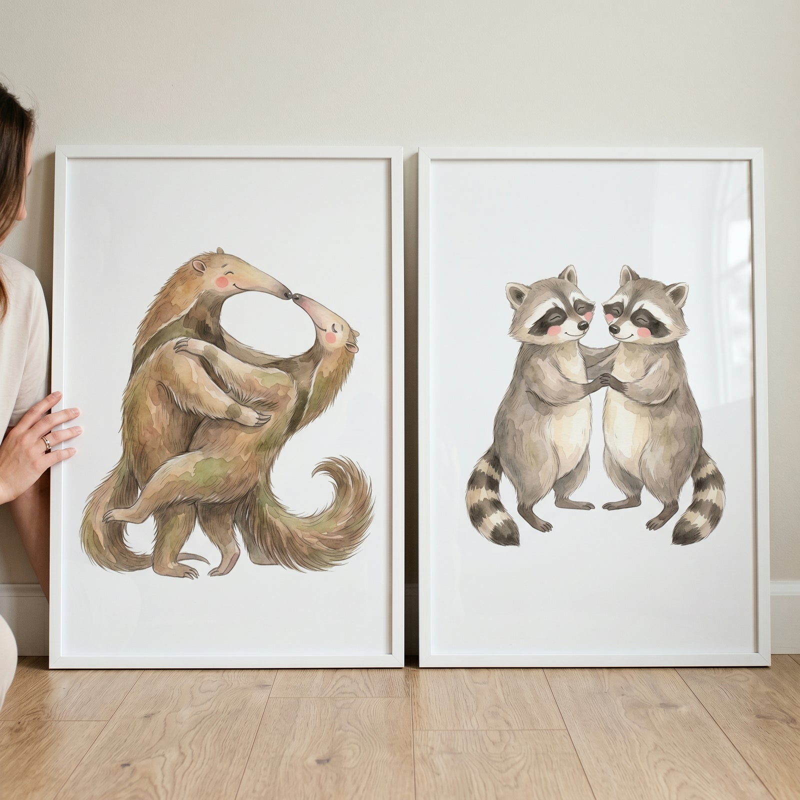 Earthy neutral hugging animals wall art set of 2 displays framed watercolor illustrations of anteaters and raccoons.