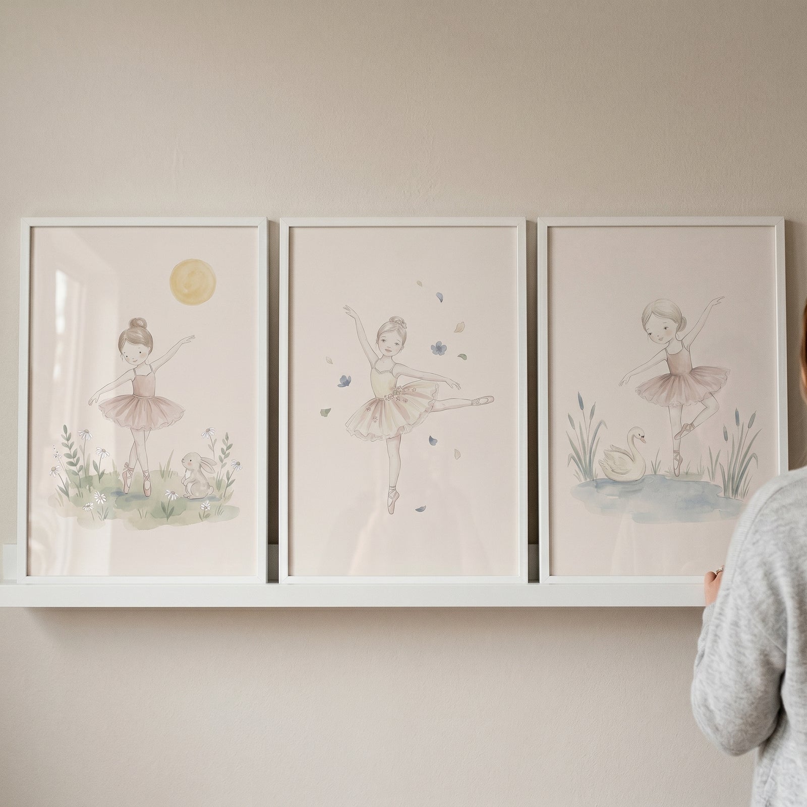 Earthy neutral watercolor ballerina artwork set of 3 displayed in white frames on a shelf against a neutral wall.