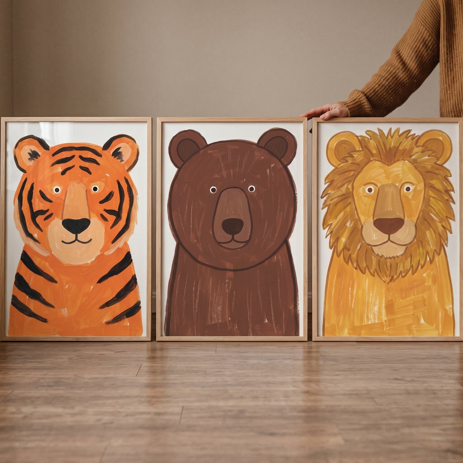 Earthy nursery wild animals wall art set of 3 with framed tiger, bear, and lion illustrations leaning on a wooden floor.