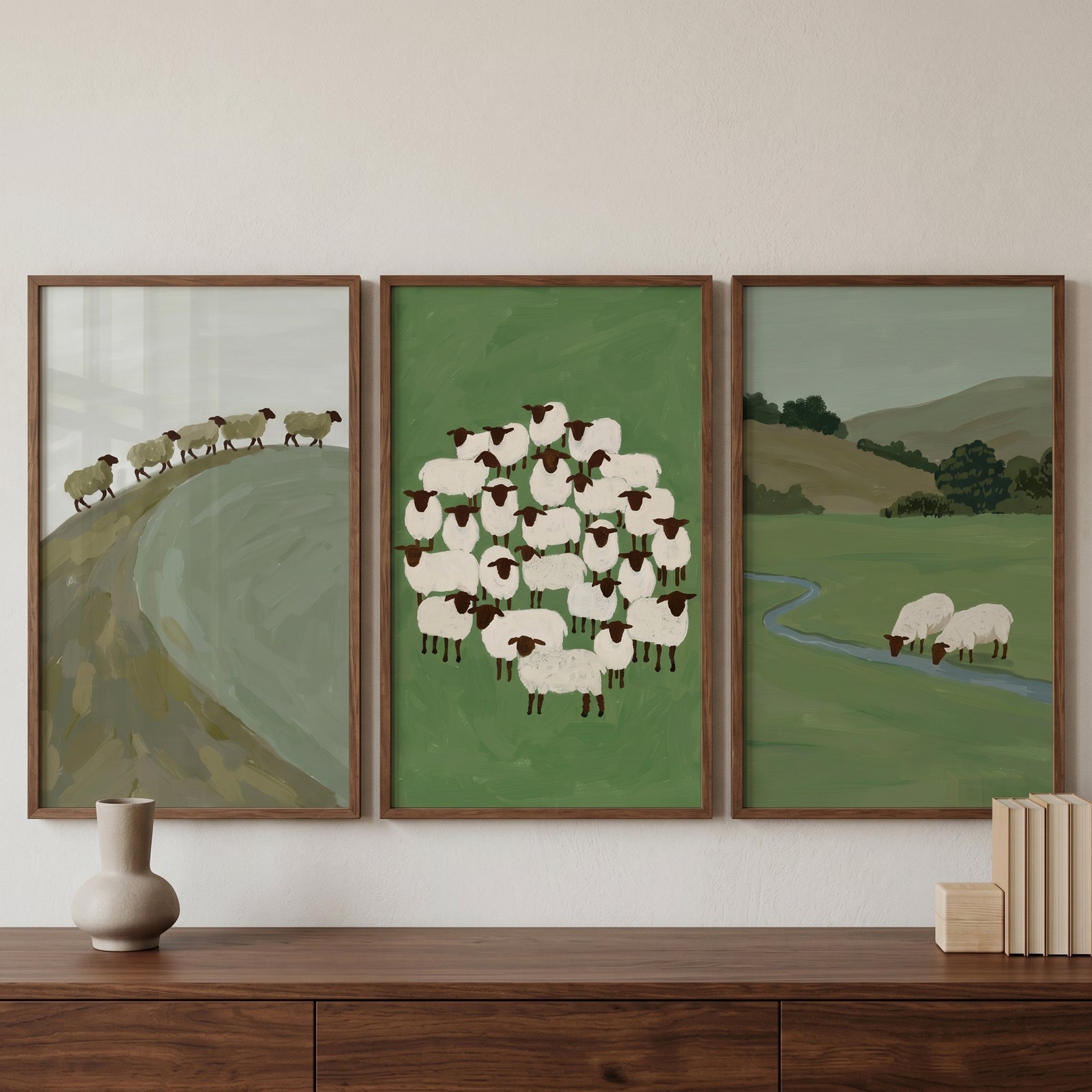 Earthy sage green sheep wall art set of 3 depicting sheep on hills, in a cluster, and by a stream in wood frames.