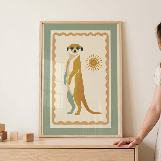 Earthy sun folk meerkat wall art in a wooden frame features a stylized animal in muted sage green and ochre tones.